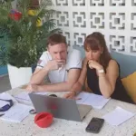 Photo de Jean-Christophe et Nathalie travaillant ensemble devant un ordinateur portable.