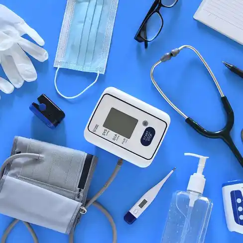 quipements médicaux sur un fond bleu, comprenant un tensiomètre, stéthoscope, masque, gants, thermomètre, désinfectant et lunettes. Accessoires essentiels pour les professionnels de santé et soins à domicile.